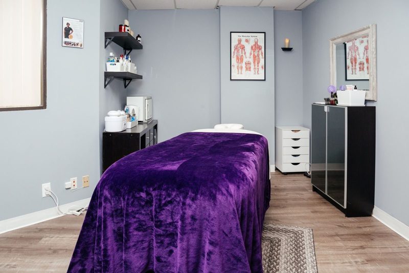 The treatment room with a purple-draped massage table