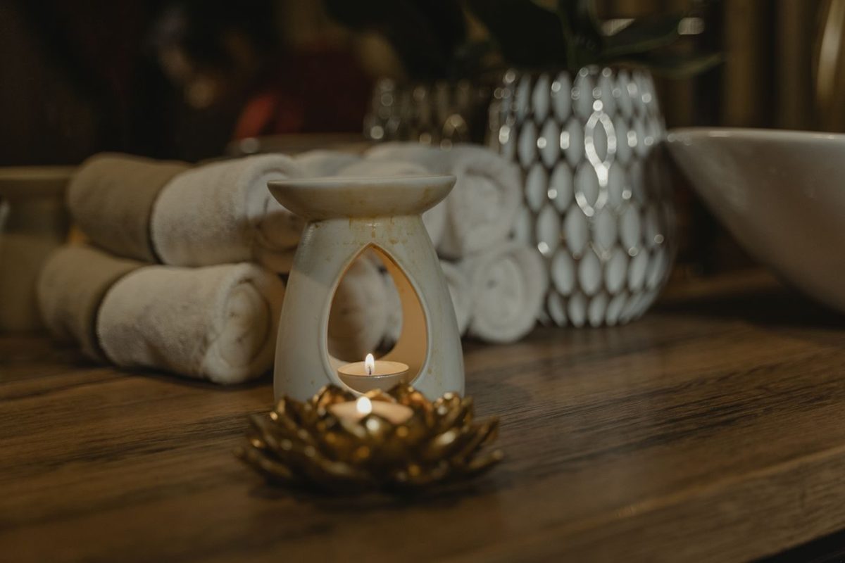An aromatherapy burner glowing beside rolled towels