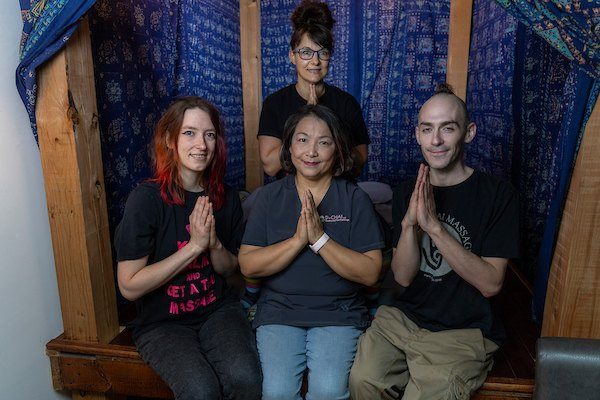 Four of the D-CHAI team sitting together in one of the studio's indigo-hung Thai rooms, hands together