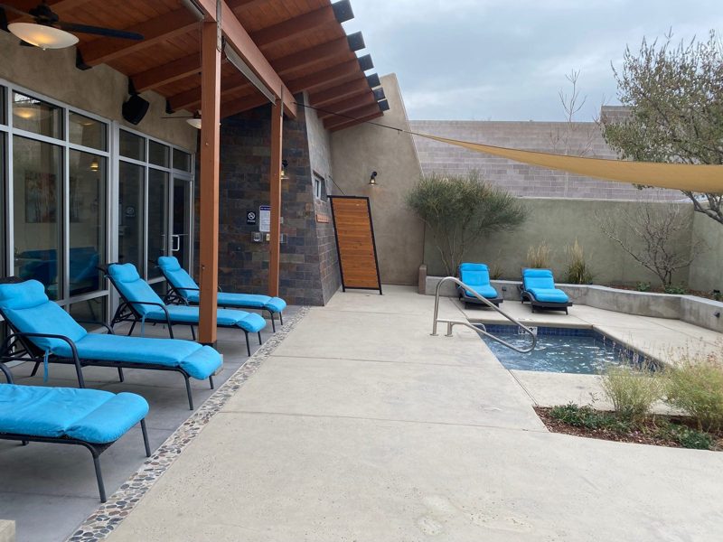 The bath courtyard with turquoise loungers, the cold plunge and a shade sail