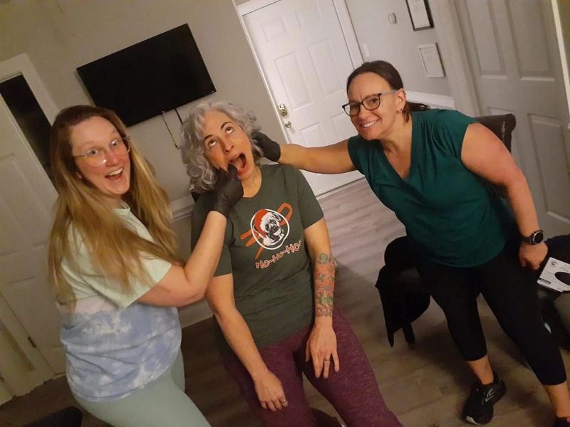 Three women smiling together in a living room after class